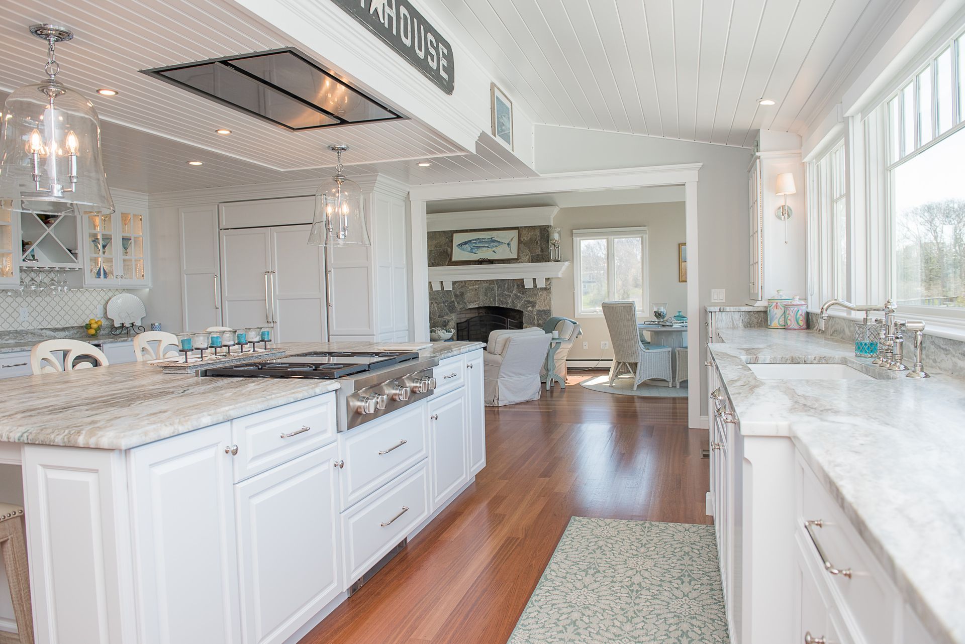 Bright white kitchen with marble counters, hardwood floors, and large windows.