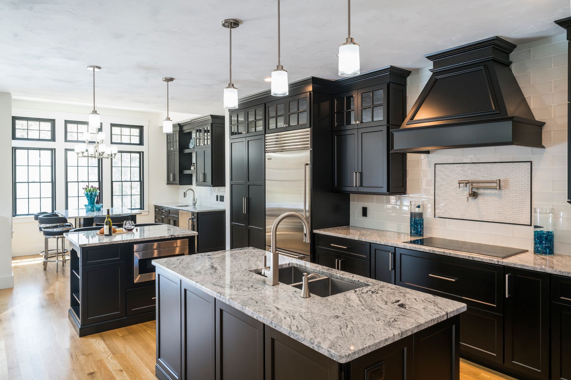 Modern black-and-white kitchen with a granite island, pendant lights, and stainless steel appliances