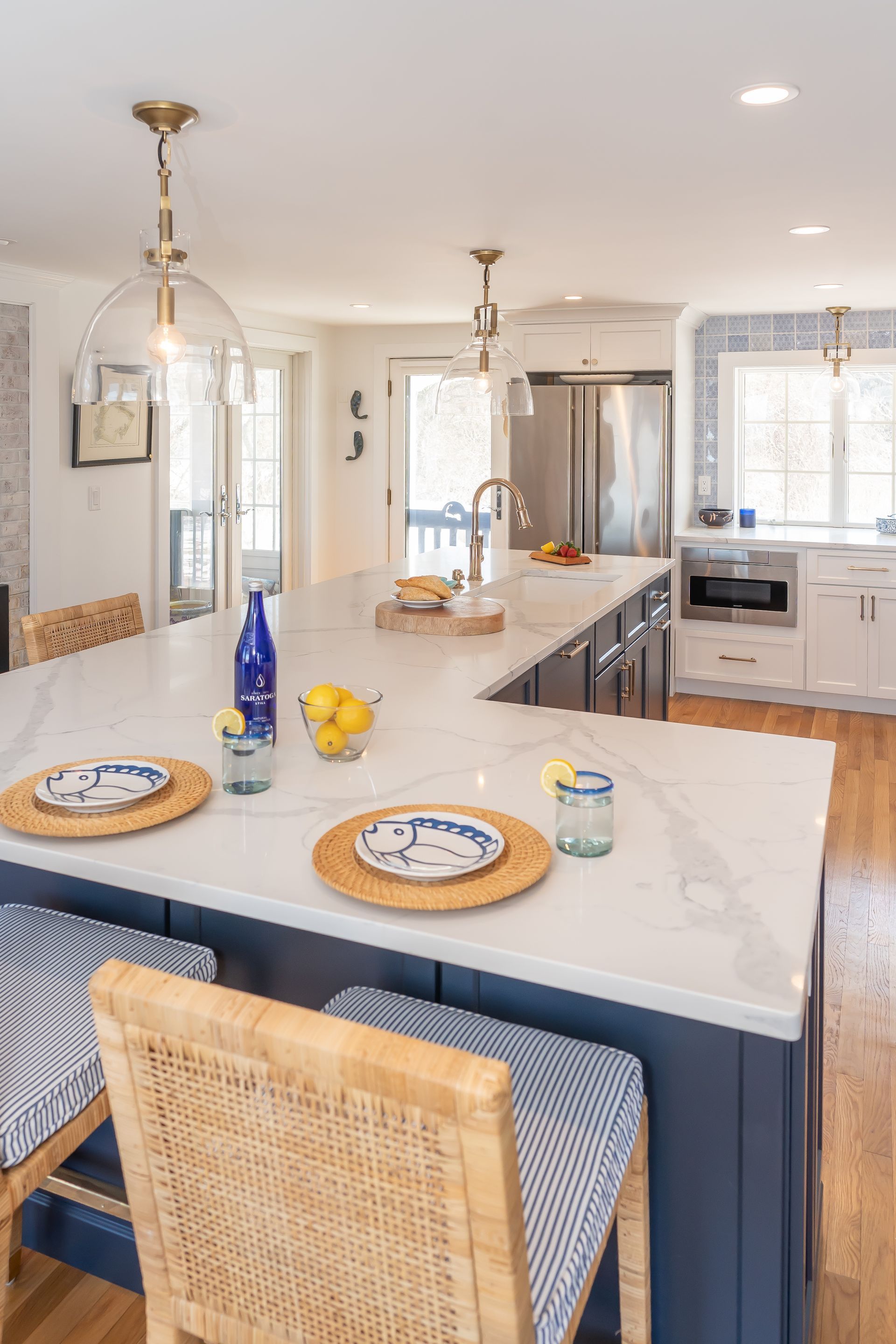 Bright modern kitchen with island, stools, pendant lights, and white cabinetry