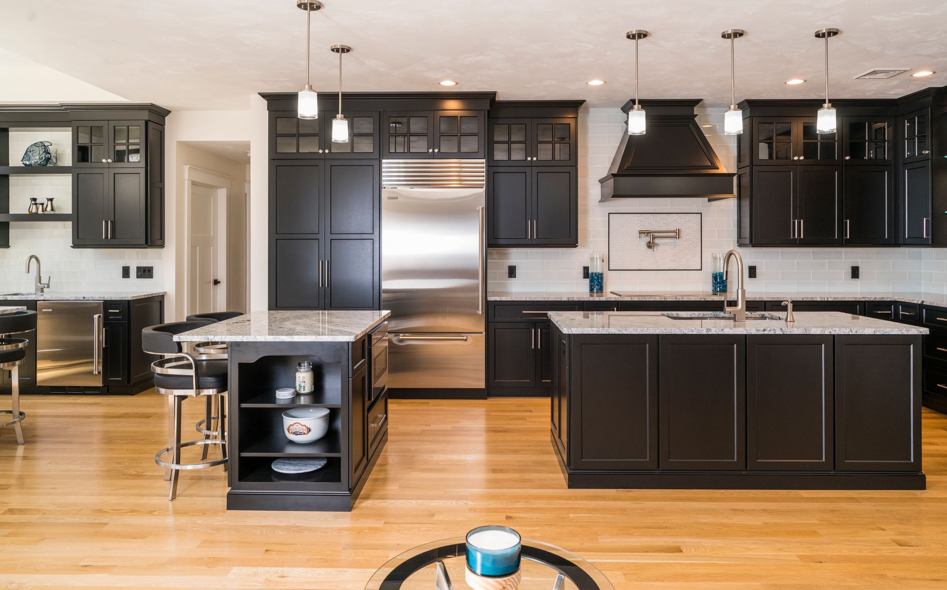 Modern kitchen with dark cabinets, stainless appliances, island, and light wood floors