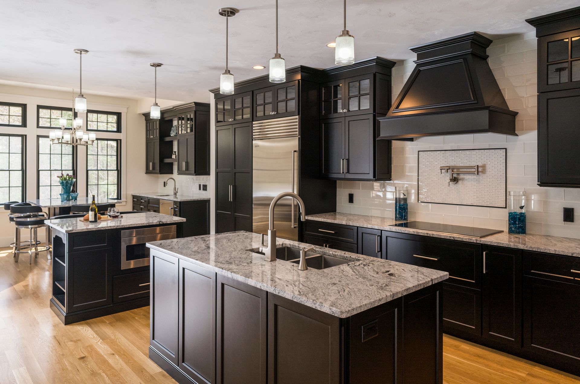Modern kitchen with dark cabinets, granite island, stainless appliances, and pendant lights