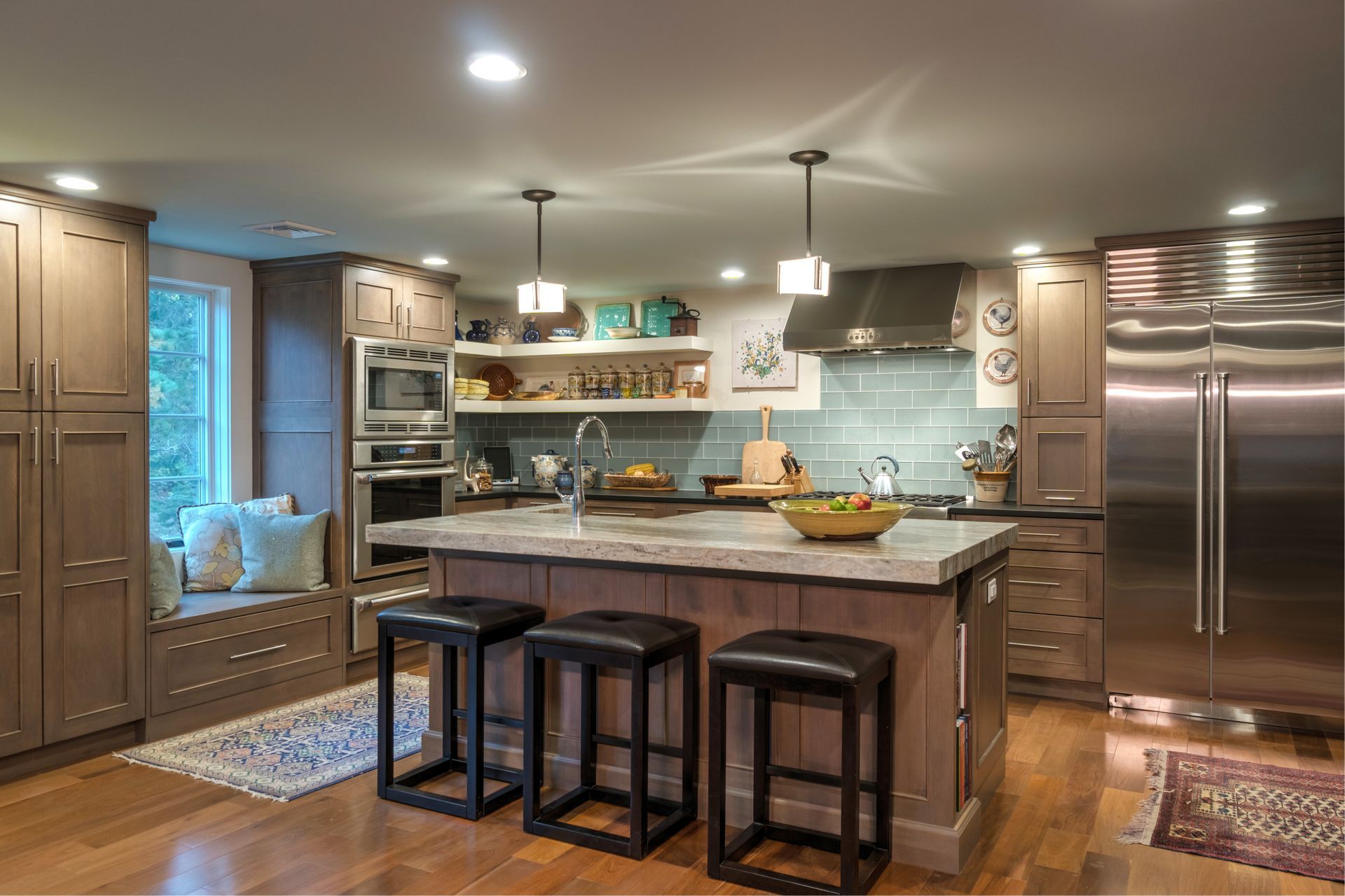 Modern kitchen with large island, bar stools, stainless steel fridge, and warm wood cabinets