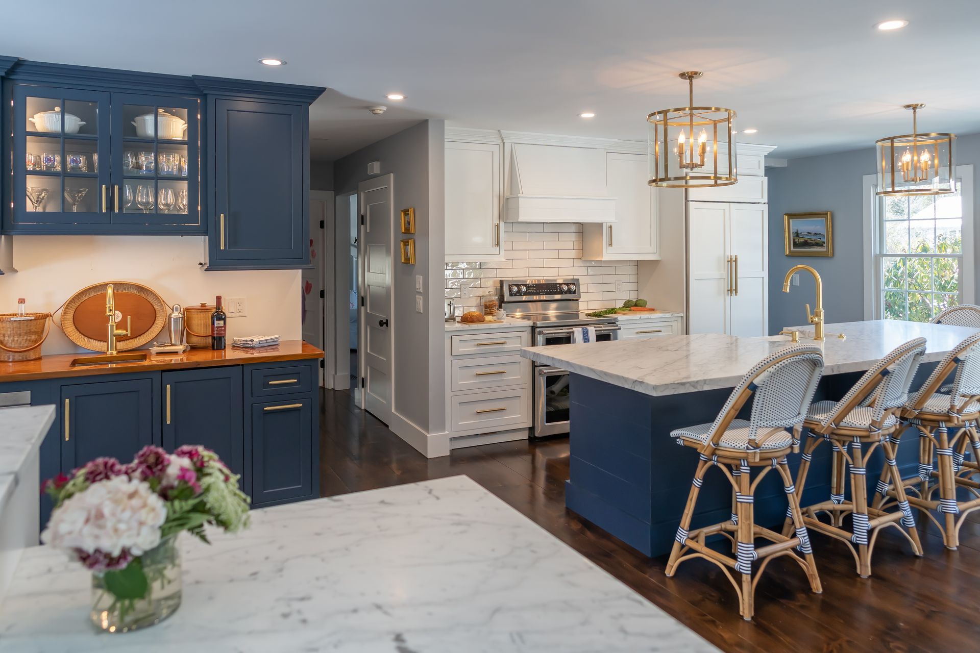 Blue-and-white kitchen with island, wicker stools, and marble countertops in a bright open layout