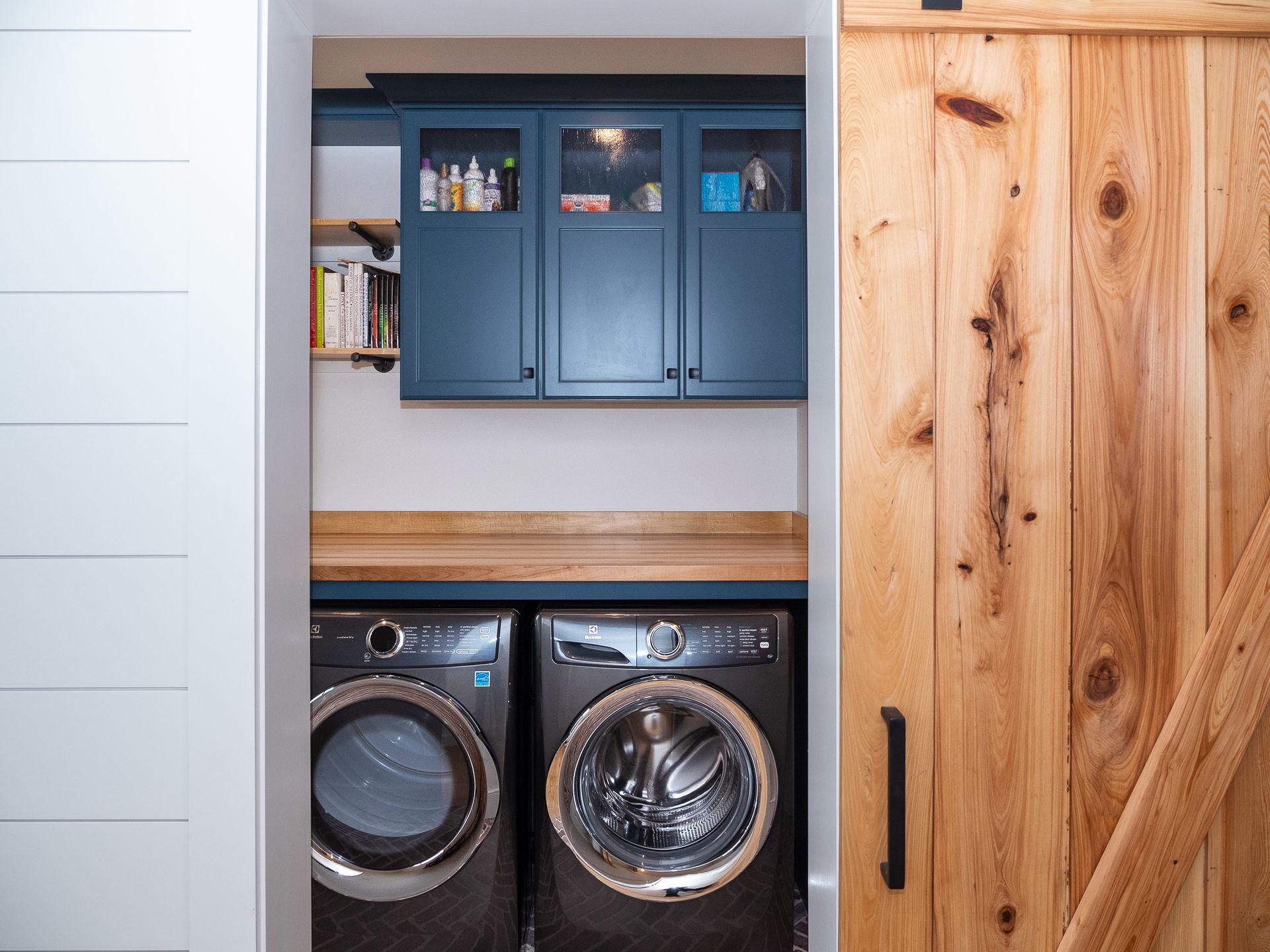 Laundry nook with blue cabinets, front-loading washer and dryer, and a wood sliding door