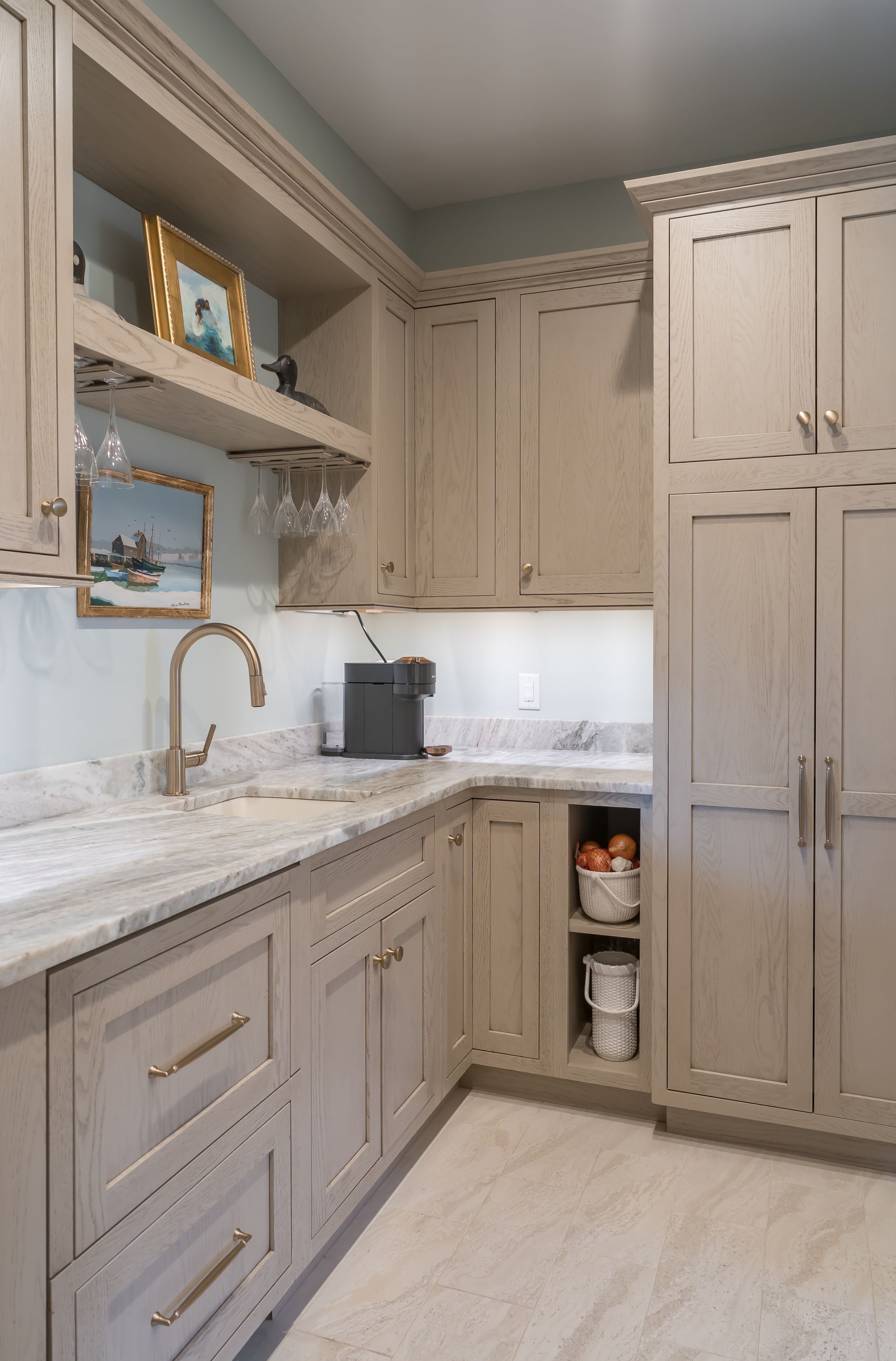 Light gray kitchen with marble countertops, white cabinets, and a stainless refrigerator.