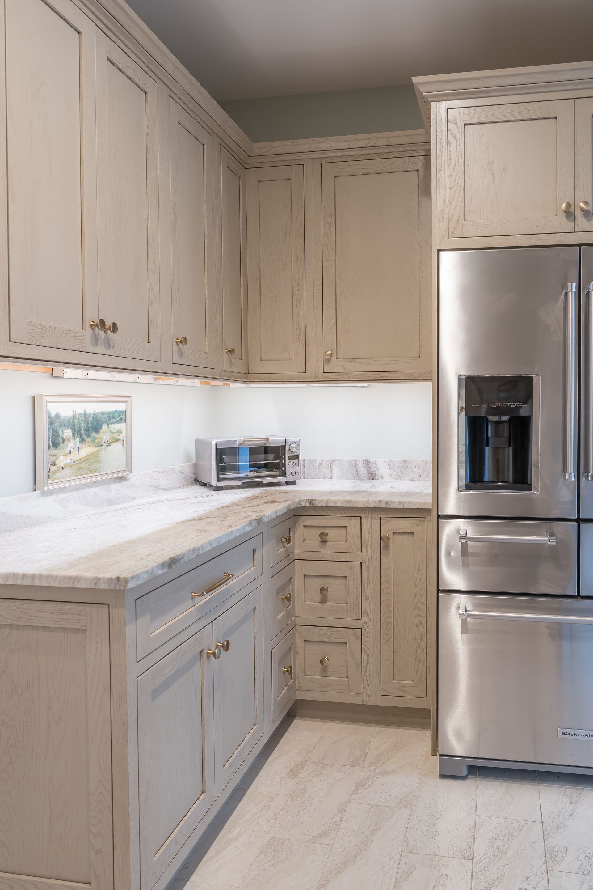 Bright white kitchen with distressed cabinets, stainless steel fridge, dishwasher, and light countertops.