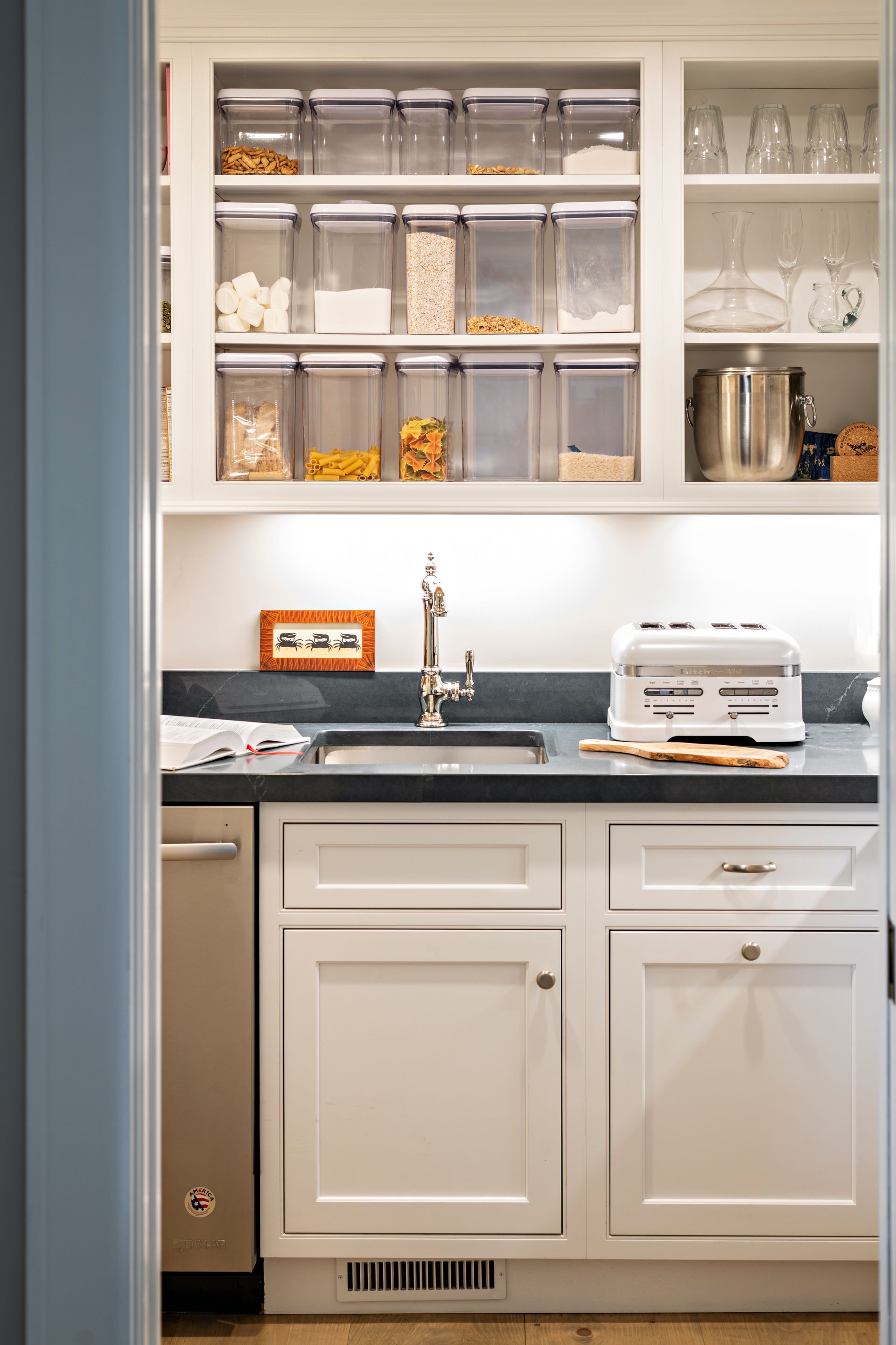 Modern kitchen wet bar with glass-front cabinets, sink, and white lower cabinets