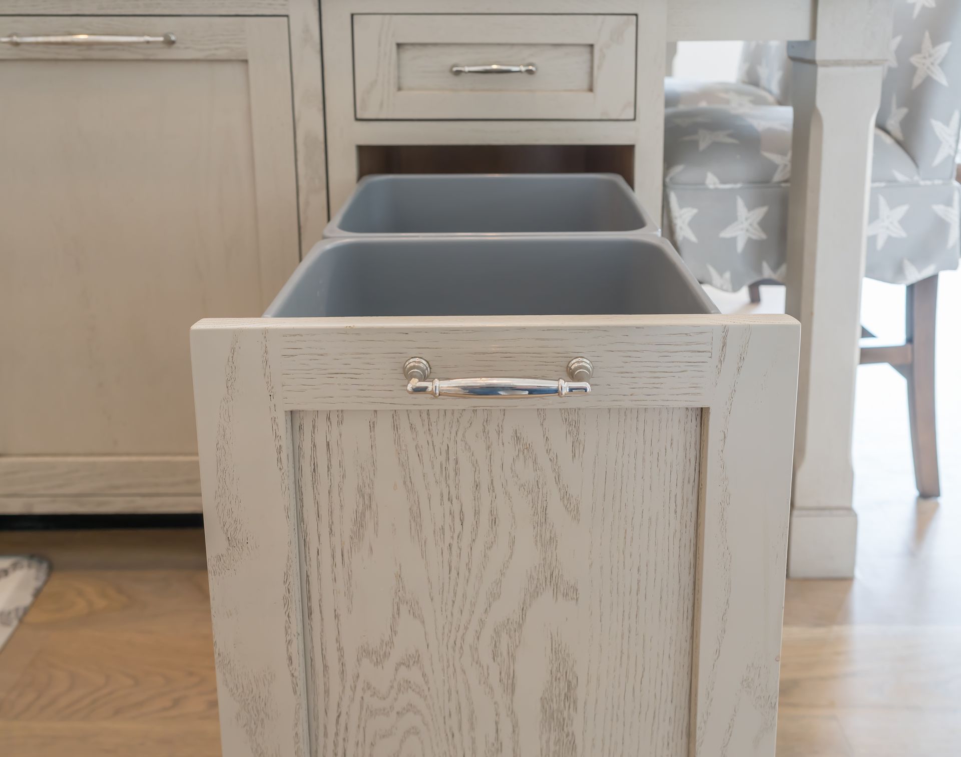 Beige woven storage bin beside a kitchen cabinet and drawers in a light wood room