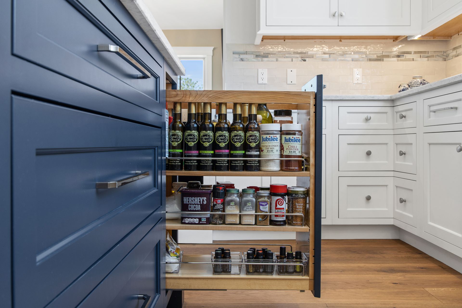 Rolling pantry shelf in a bright kitchen, stocked with bottles, jars, and canned goods.