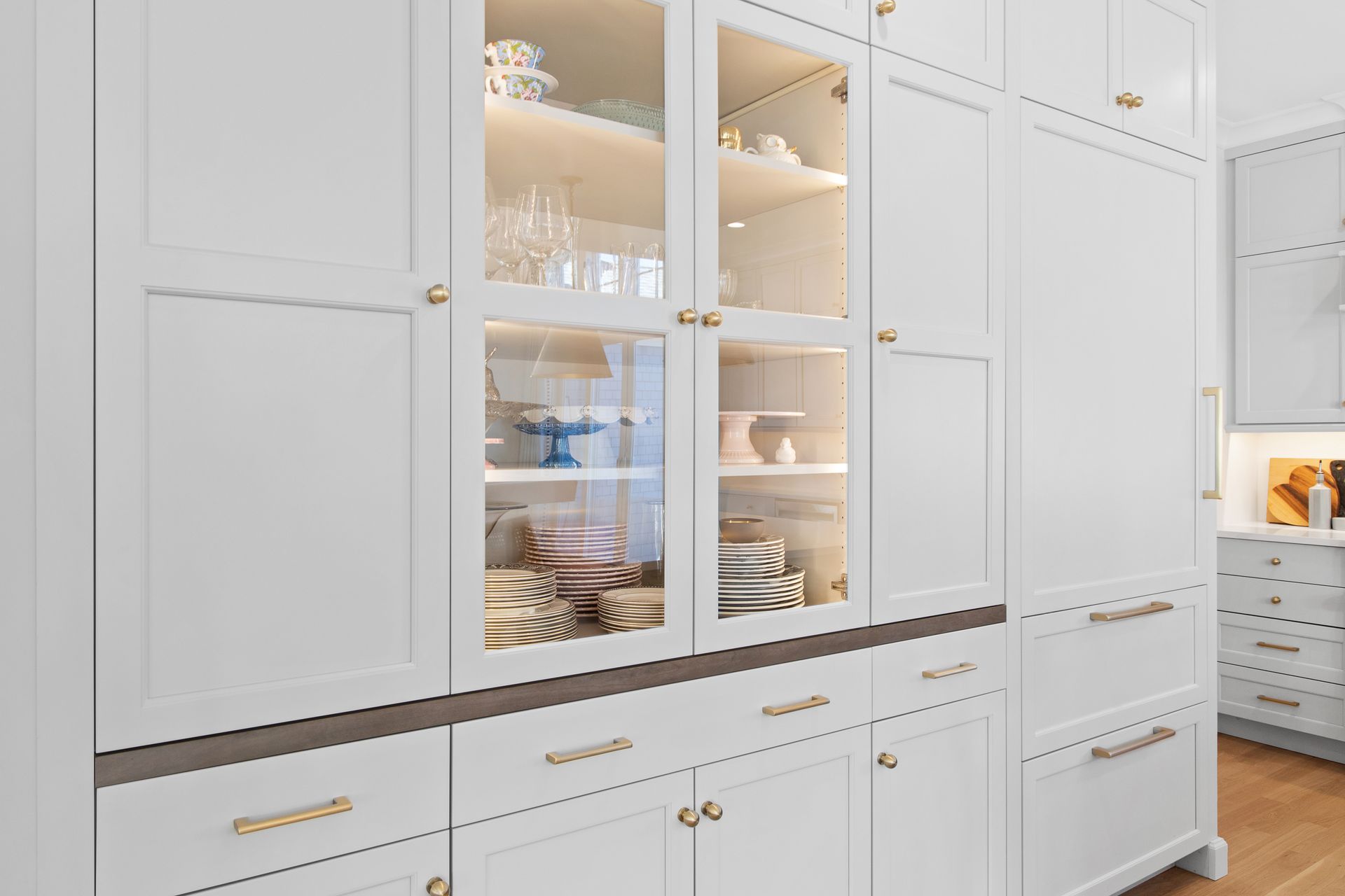 Built-in white kitchen cabinets with glass-front shelves displaying dishes and glassware
