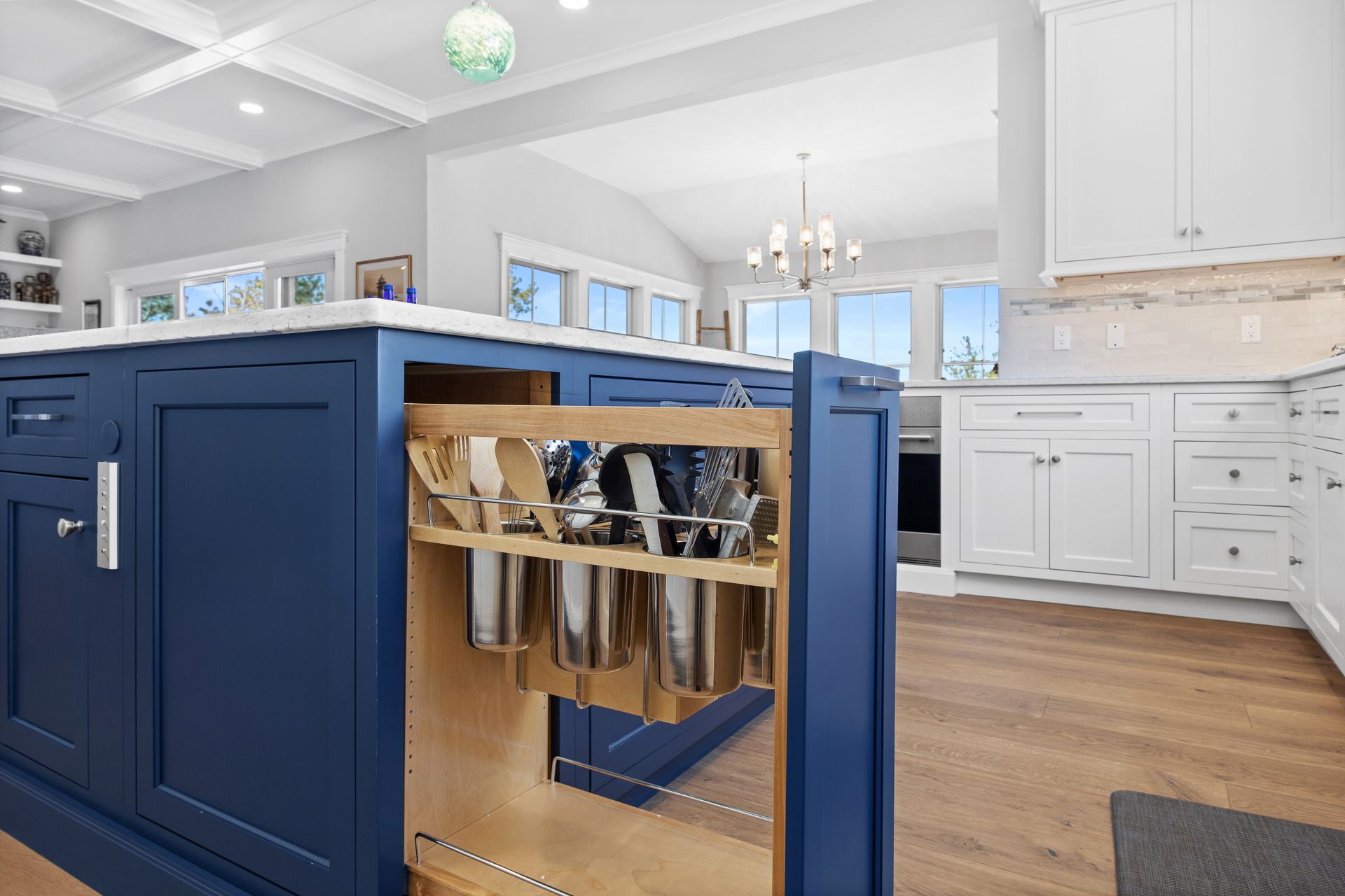 Blue kitchen island with pull-out dish racks in a bright white kitchen