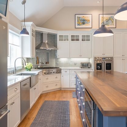 Bright modern kitchen with white cabinets, wood countertops, pendant lights, and a central island