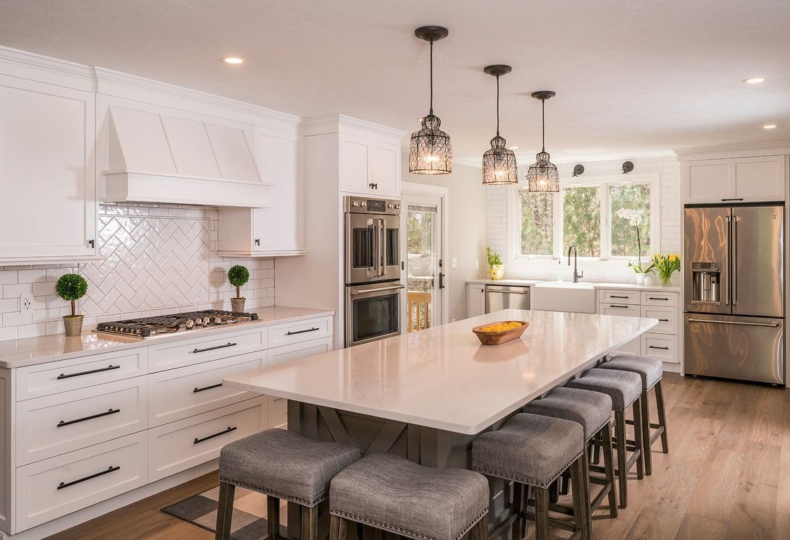 Bright modern kitchen with white cabinetry, marble island, pendant lights, and stainless steel appliances
