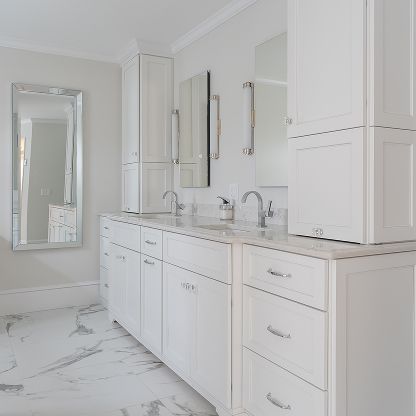 Bright white bathroom vanity with double sinks, mirrors, and marble floor and countertops