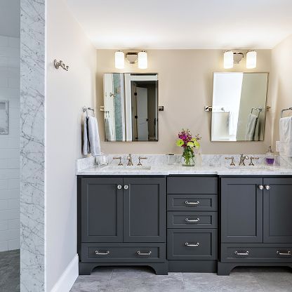 Modern bathroom with dark double vanity, marble countertop, mirrors, and wall sconces