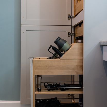 Wooden pull-out shelf with camera gear beside a wall and cabinet in a small room
