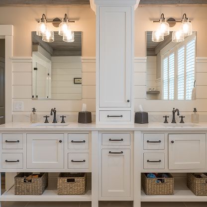 Elegant double vanity bathroom with white cabinets, large mirrors, dual faucets, and woven storage baskets underneath