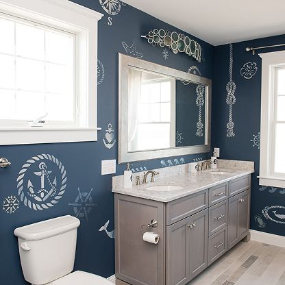 Blue bathroom with chalkboard-style wall art, gray vanity, white sink, and toilet near a window