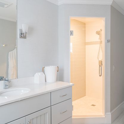 Modern bathroom with white vanity and a lit walk-in shower stall