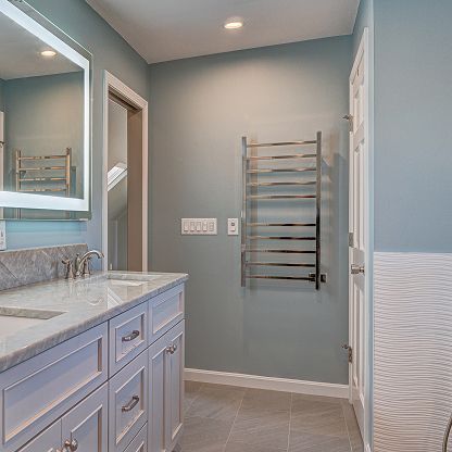 Modern bathroom with gray walls, white vanity, mirror, towel warmer, and tiled floor