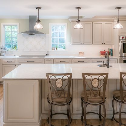 Bright white kitchen with island, pendant lights, cabinets, and two barstools