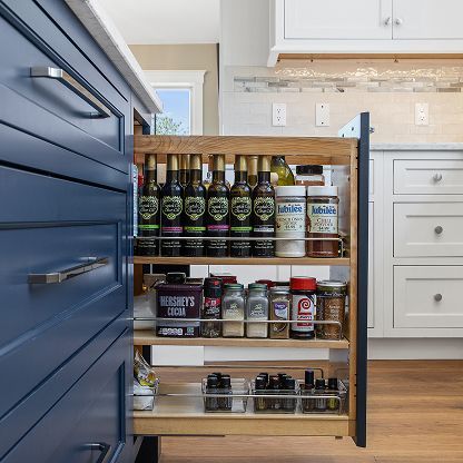 Pull-out pantry drawer stocked with condiments and bottles in a bright kitchen