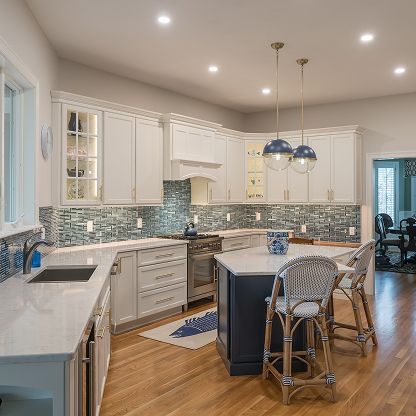 Bright modern kitchen with white cabinets, blue tile backsplash, island, and pendant lights