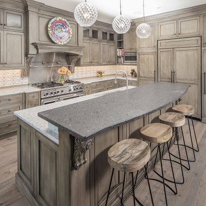 Modern kitchen with gray cabinetry, large island, pendant lights, and four stools