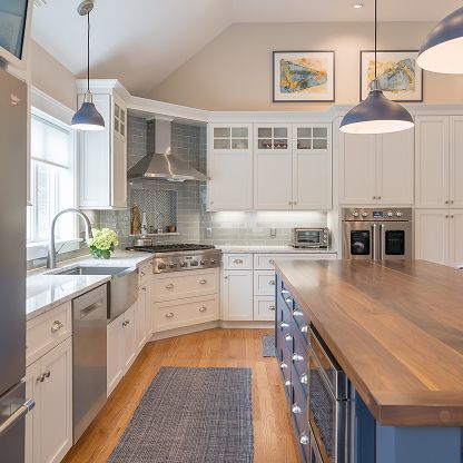 Bright modern kitchen with white cabinets, wood island, stainless appliances, and a gray runner rug