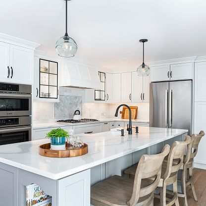 Bright modern white kitchen with island, stainless steel fridge, pendant lights, and bar stools