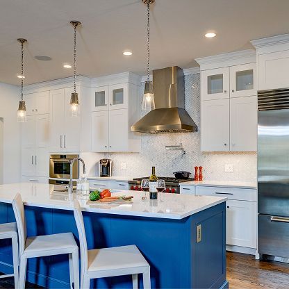 Bright modern kitchen with blue island, white cabinets, stainless hood, and bar stools