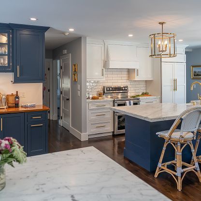Modern kitchen with blue and white cabinets, marble island, and wicker barstools