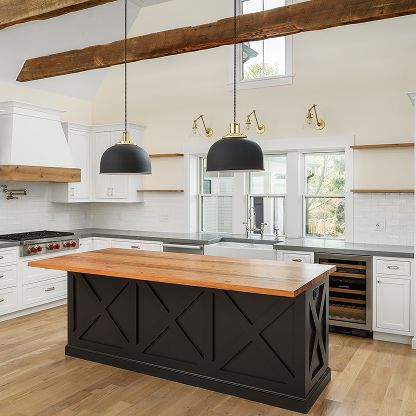 Bright modern kitchen with wood island, black pendants, white cabinets, and exposed ceiling beams