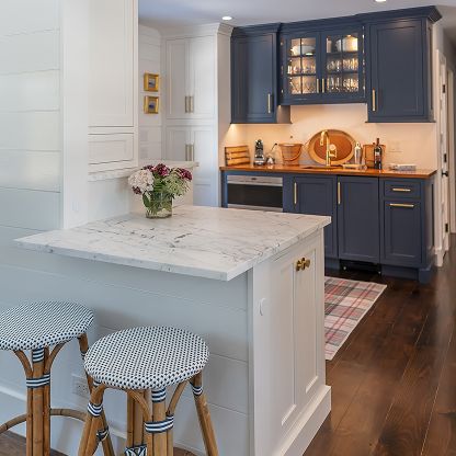 Bright kitchen with navy cabinets, white island, and two patterned stools