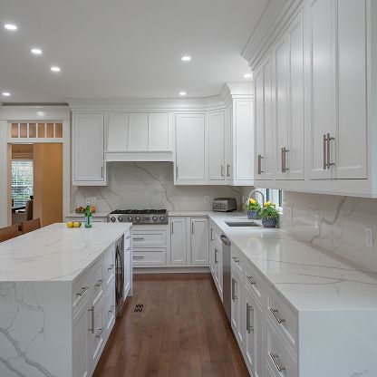Bright modern white kitchen with marble island, stainless range, and dark wood floors