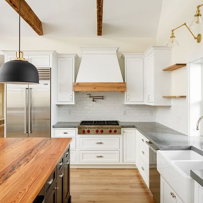 Bright modern kitchen with white cabinets, wood island, stainless fridge, and open shelves