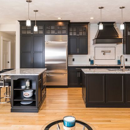 Modern kitchen with dark cabinets, stainless steel appliances, granite island, and hardwood floors