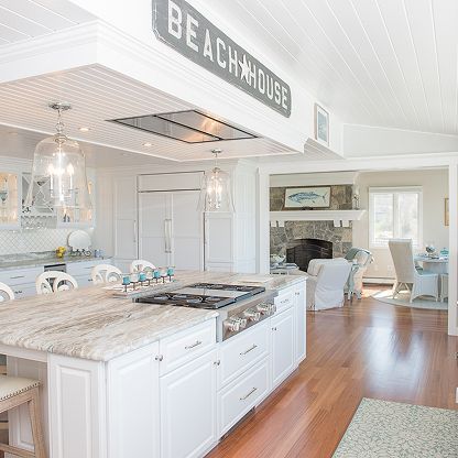 Bright beach-house kitchen with white cabinets, island, and open view to a cozy living room