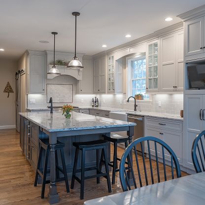 Bright modern kitchen with gray cabinets, large island, pendant lights, and blue chairs