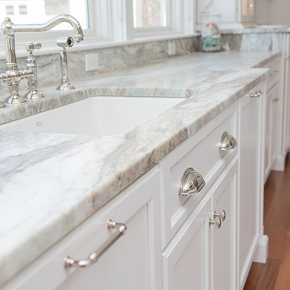 Bright white kitchen sink with marble countertop and chrome faucet in a clean, modern interior