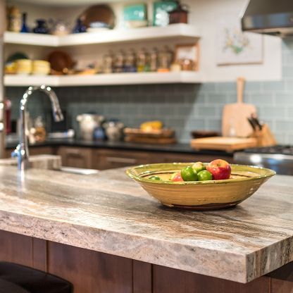Modern kitchen with a marble island and a bowl of fruit in the foreground