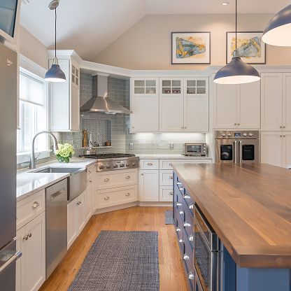 Bright modern kitchen with white cabinets, wood island, stainless appliances, and pendant lights
