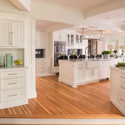 Bright, modern white kitchen with island, stainless appliances, and hardwood floors