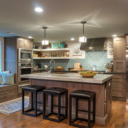 Modern kitchen with island, three stools, pendant lights, and light blue tile backsplash