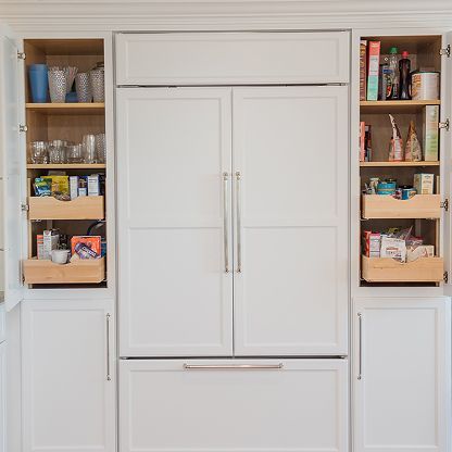 White built-in pantry cabinets with open shelves stocked with food and drinks.