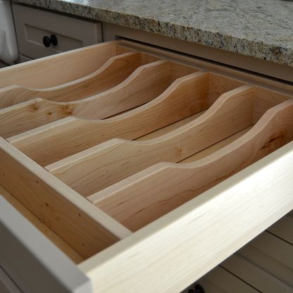 Open kitchen drawer with wooden dividers for organizing utensils and cutlery.