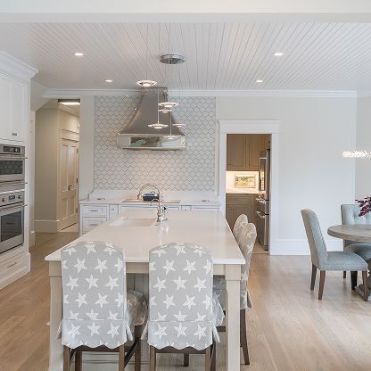 Bright modern kitchen with white island, patterned chairs, pendant lights, and adjoining dining area