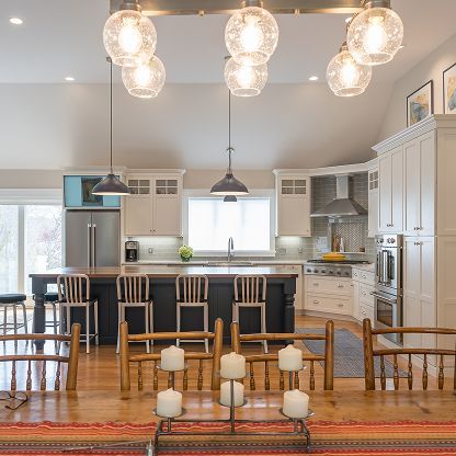 Bright modern kitchen with white cabinets, black island, pendant lights, and wooden bar stools