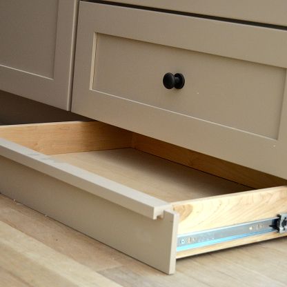 Open drawer with blue metal slides in a beige kitchen cabinet