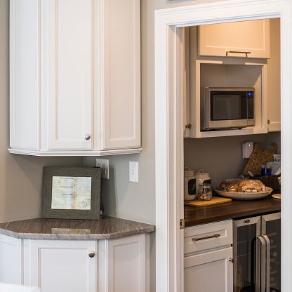 Built-in kitchen cabinetry with granite countertop and a doorway to a small coffee nook with microwave and snacks